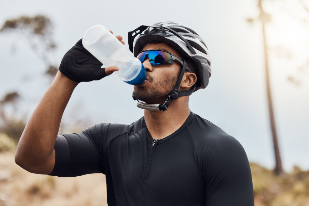 un cycliste en extérieur qui boit dans une gourde